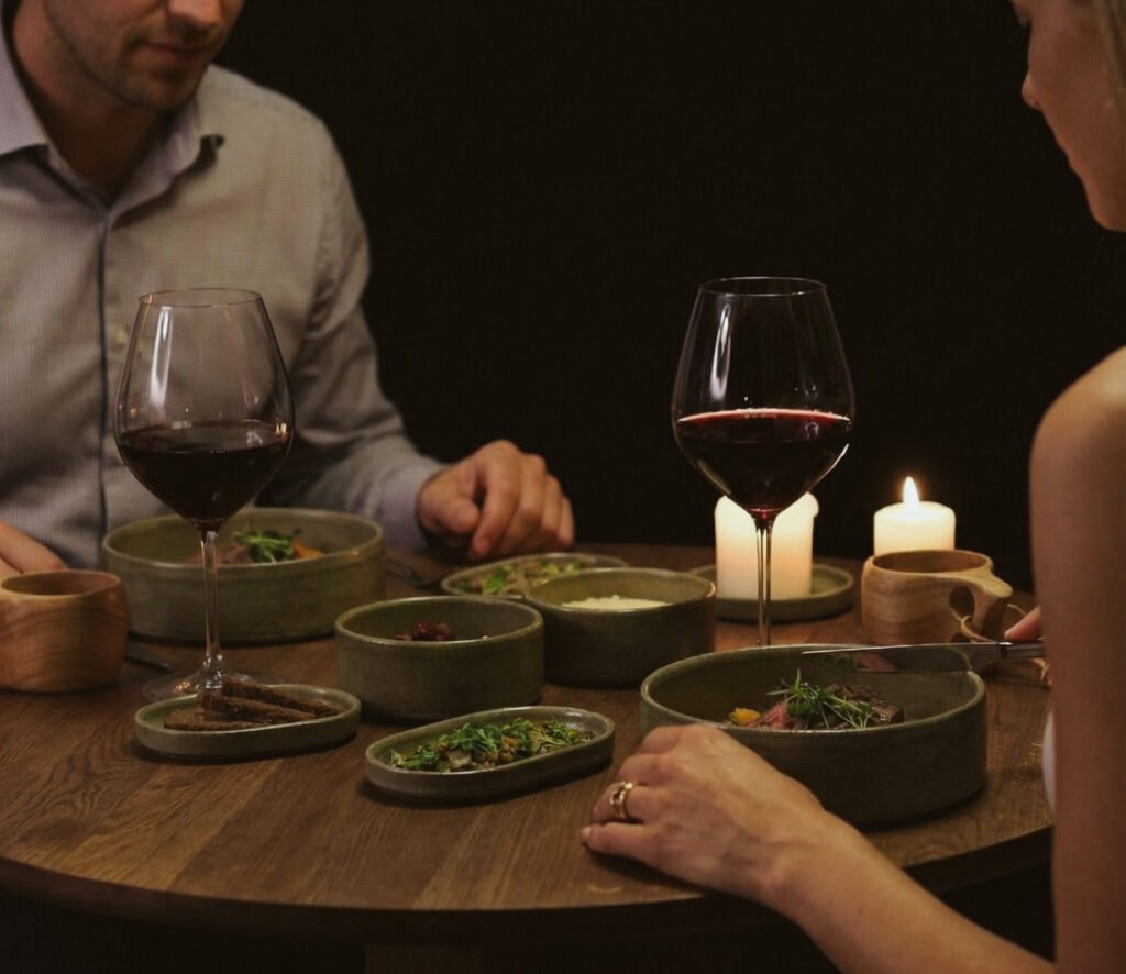 Guests enjoying a candlelit tasting dinner with plated dishes and red wine.