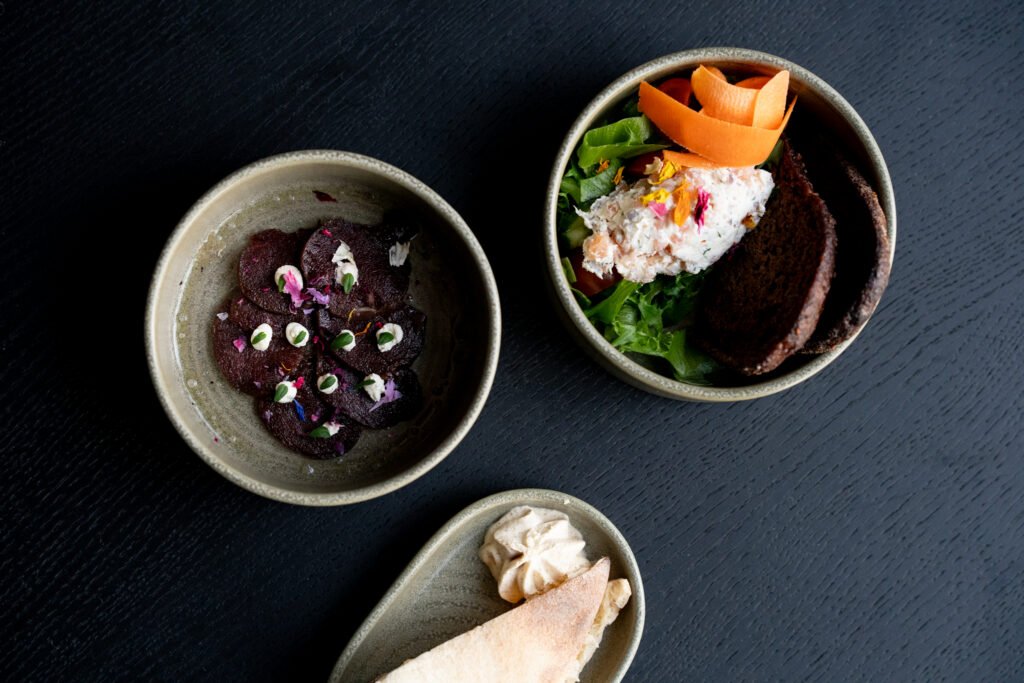 Seasonal dishes served in ceramic bowls with beetroot, salad, vegetables and bread.
