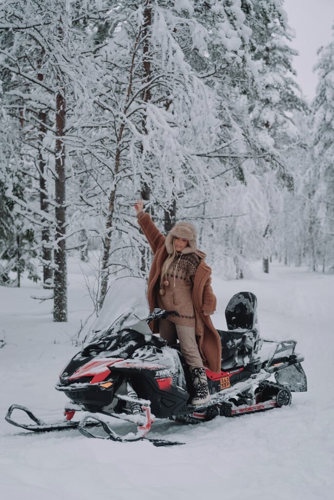 A person riding a snowmobile through a snow-covered Lapland forest.