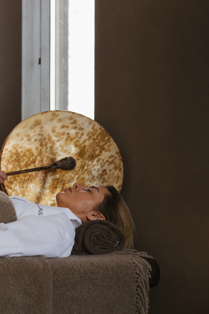 Woman relaxing during a wellness sound treatment with a shaman drum.