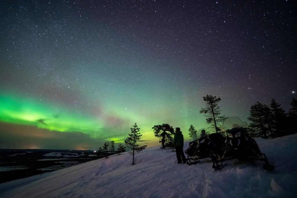Electric snowmobiles beneath the Northern Lights in Finnish Lapland.