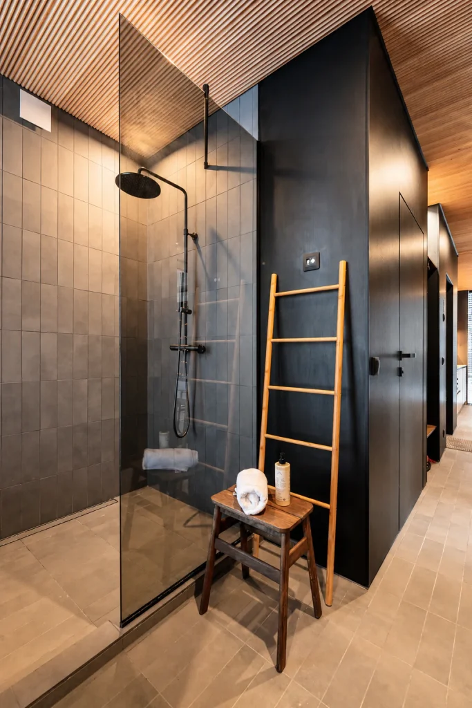 Deluxe Villa bathroom with a walk-in rainfall shower and warm Nordic finishes.