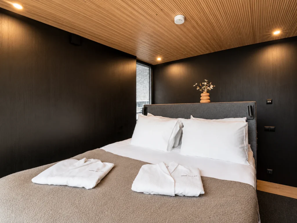 Deluxe Villa bedroom with a double bed, dark walls and a warm timber ceiling.