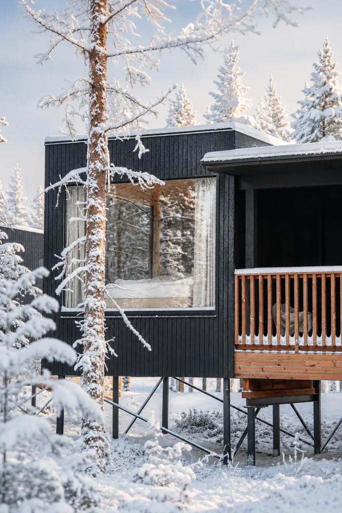 Side view of the Deluxe Villa and its private terrace in a snowy Lapland forest.