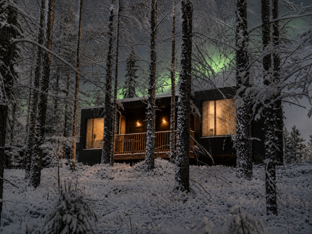 Deluxe Villa exterior surrounded by snow-covered pine trees in Finnish Lapland.