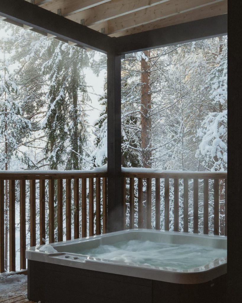Private outdoor hot tub on a villa terrace overlooking a snowy forest.