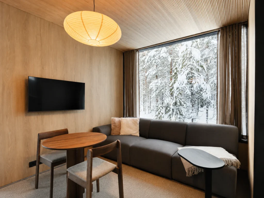 Standard Villa living room with a dining table and floor-to-ceiling forest views.